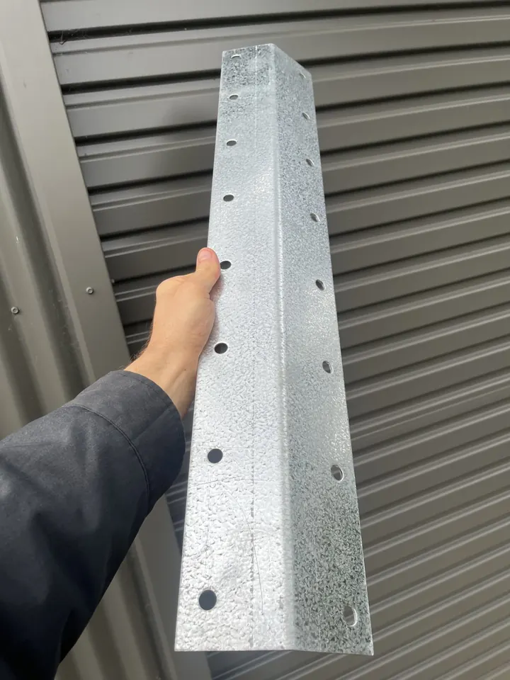 Stewart holding one of the galvanised steel corner brackets against a shed wall