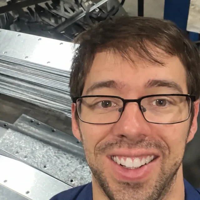Stewart, the founder, smiling in the workshop with a batch of finished corner supports